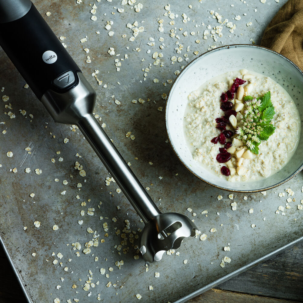 A black and silver ESSENTIAL POWER set with a powerful motor and stepless speed control, featuring three components: the blender handle, a clear measuring pitcher filled with chopped red onions, and a clear food processor attachment containing chopped vegetables, including red onions and green peppers.