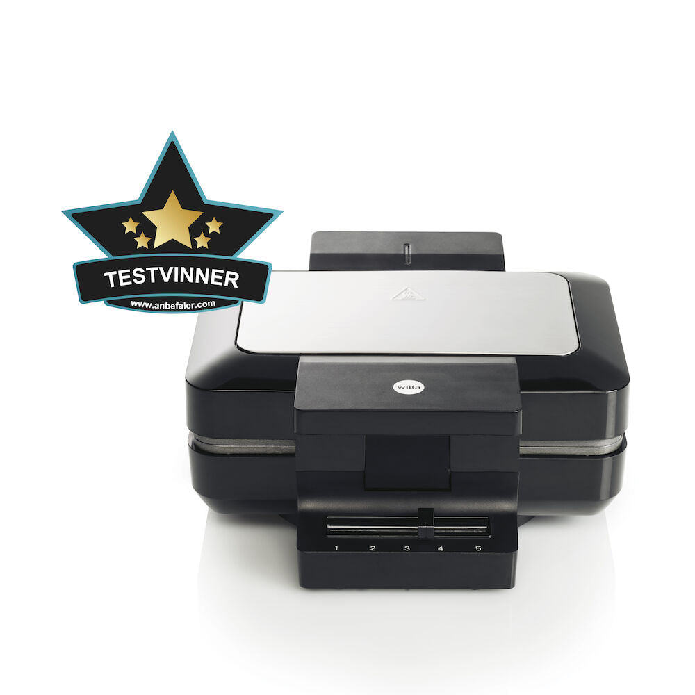 A sleek black GAUFRES BELGIAN with silver accents is pictured against a white background. A gold and black badge with the text "TESTVINNER" is displayed in the top left corner, indicating it has been awarded a test winner. The waffle maker features adjustable temperature and double release coating for perfect waffles every time.